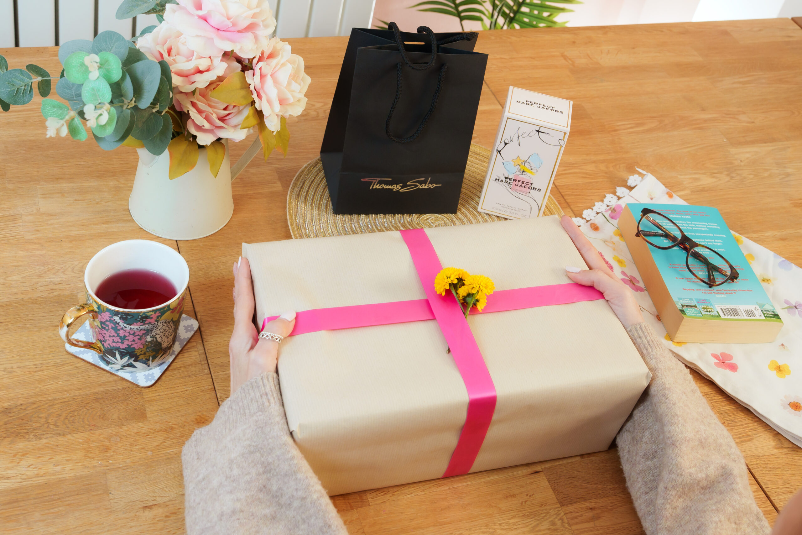 Mother’s Day gift bundle with wrapped present, perfume, flowers and tea