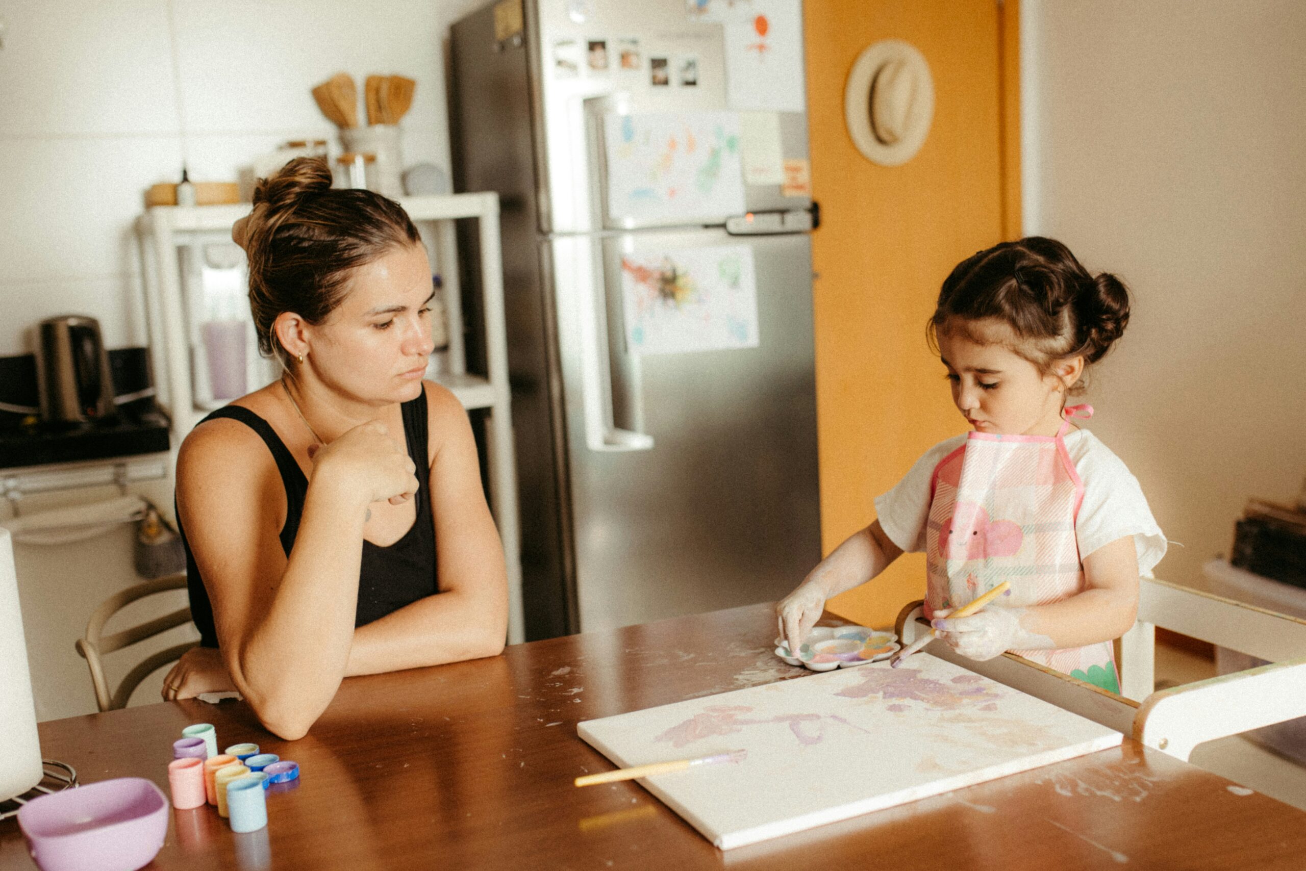 : A parent helping a child with homework at a kitchen table 