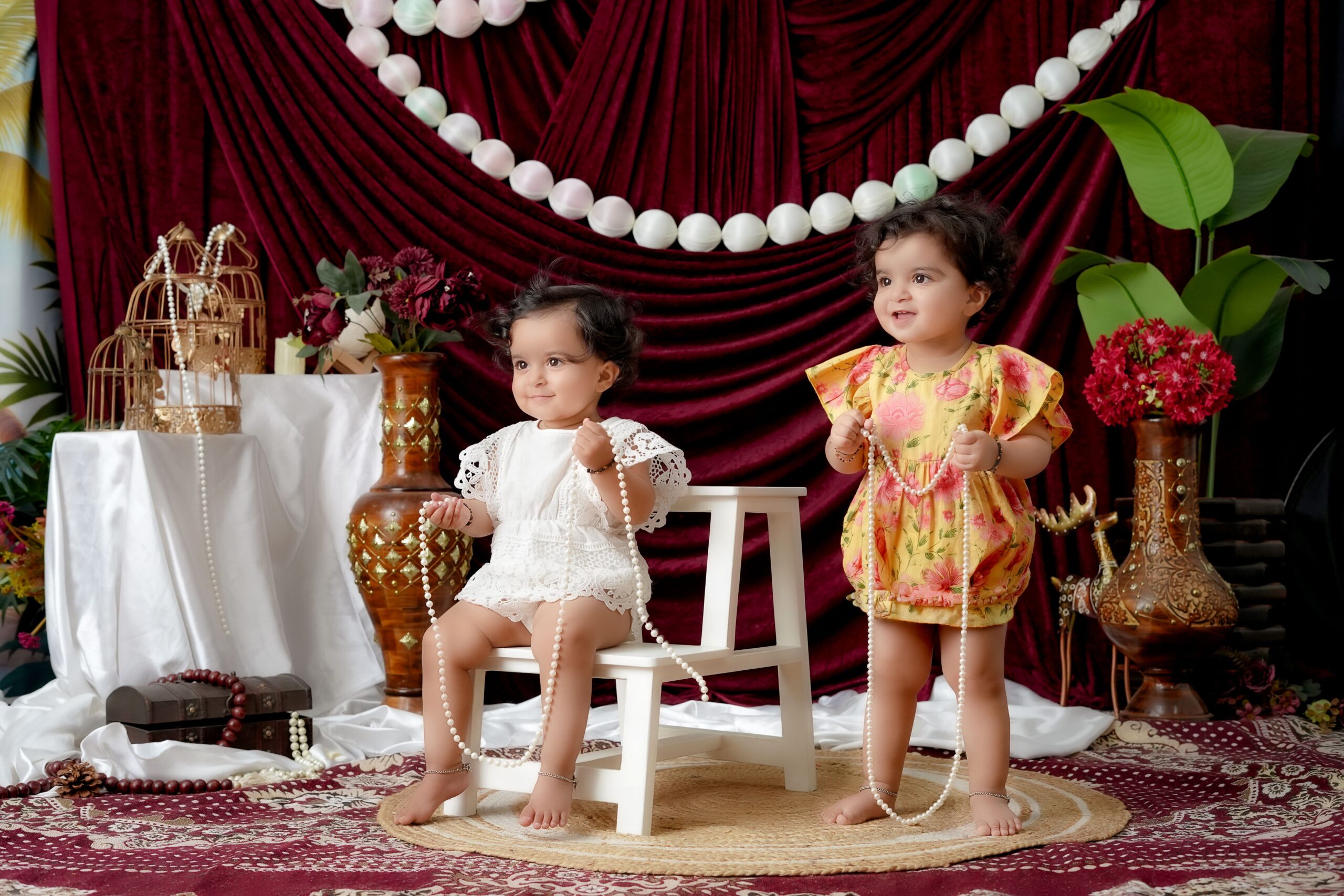Two toddlers enjoying an indoor photoshoot with elegant decor